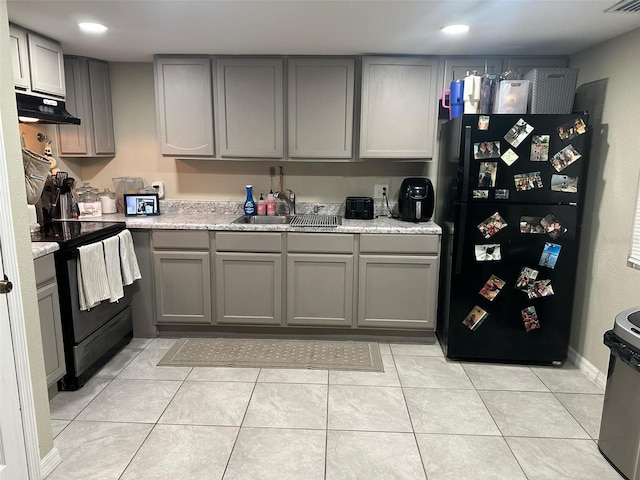 kitchen with black appliances, sink, gray cabinets, light stone counters, and light tile patterned floors