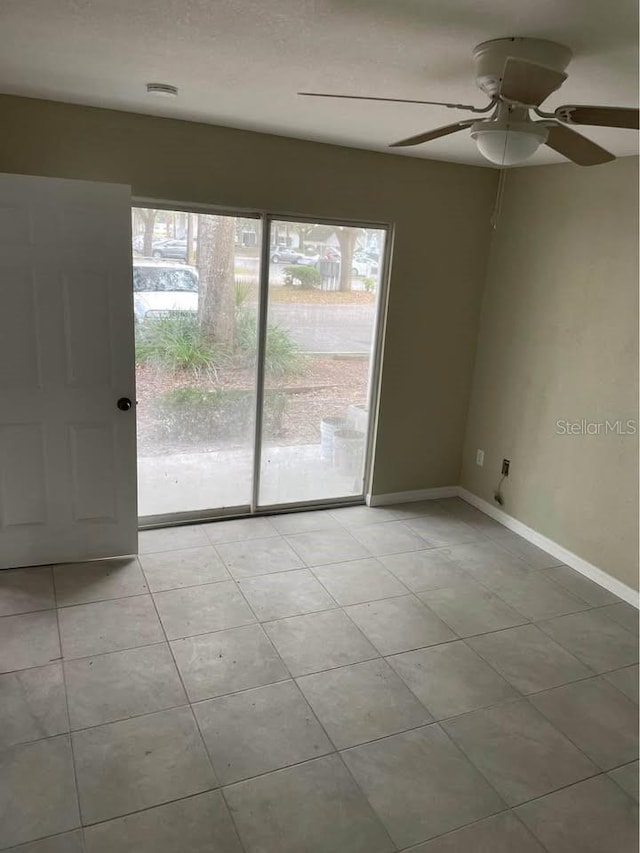 tiled spare room featuring ceiling fan