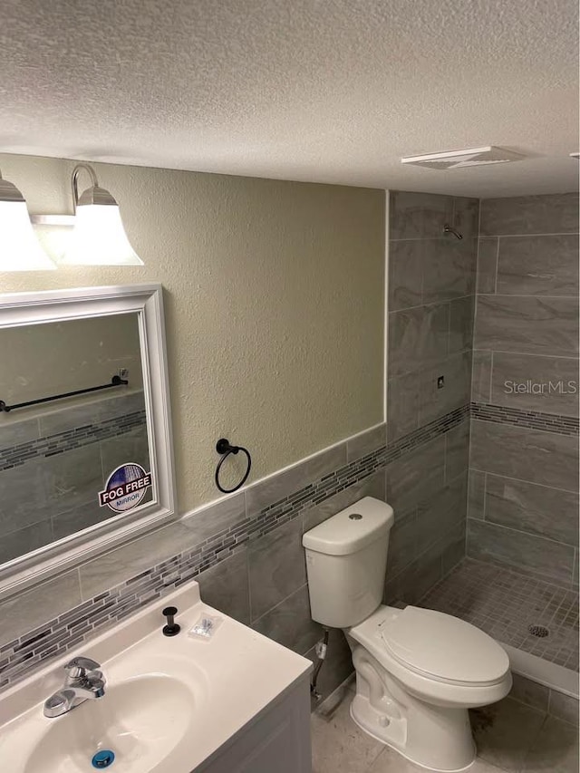 bathroom with toilet, tile walls, tile patterned flooring, a textured ceiling, and a tile shower