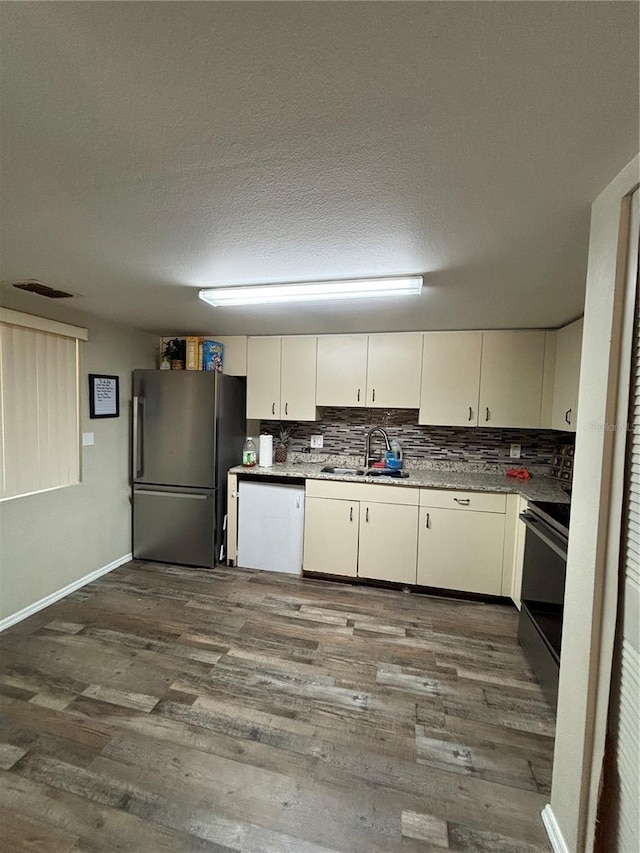 kitchen featuring dark hardwood / wood-style floors, sink, a textured ceiling, stainless steel appliances, and cream cabinets