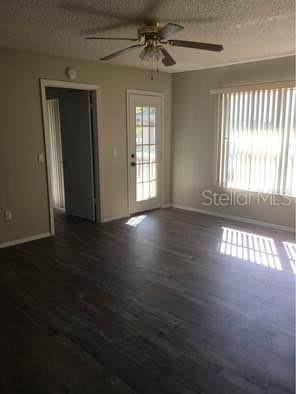 empty room featuring a textured ceiling, ceiling fan, and dark hardwood / wood-style flooring