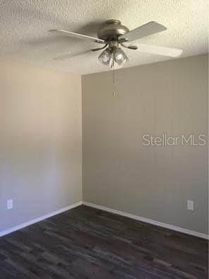 spare room featuring ceiling fan, dark wood-type flooring, and a textured ceiling