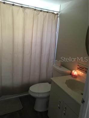 bathroom featuring toilet, vanity, and a shower with shower curtain