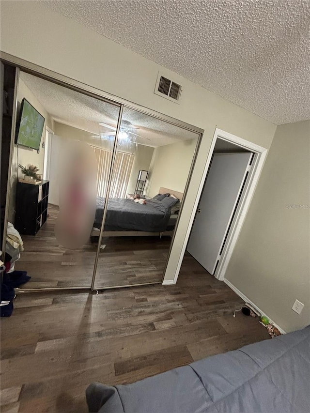 bedroom featuring a textured ceiling, dark hardwood / wood-style floors, and a closet