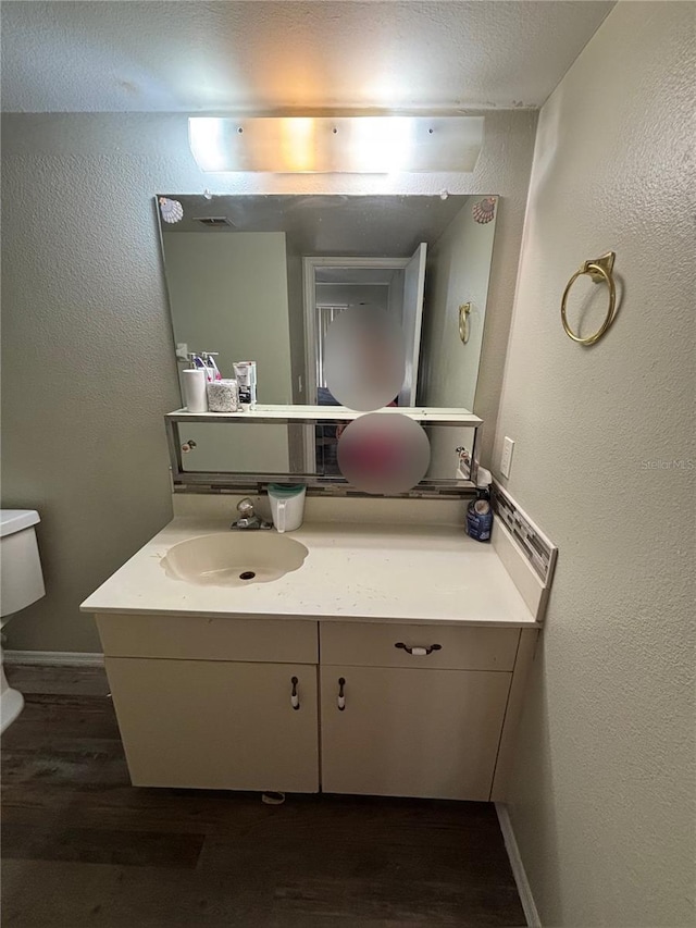 bathroom featuring toilet, hardwood / wood-style flooring, and vanity