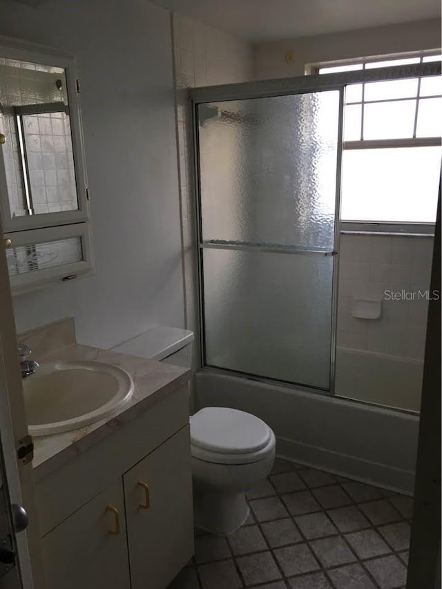 full bathroom with combined bath / shower with glass door, vanity, toilet, and tile patterned flooring