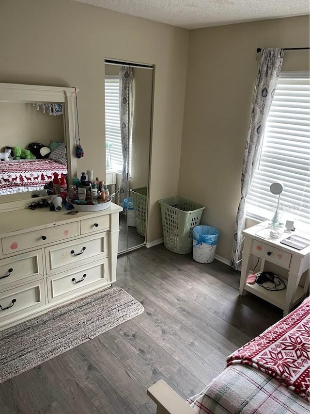 bedroom with multiple windows, a textured ceiling, a closet, and dark hardwood / wood-style flooring