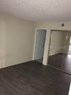 unfurnished bedroom with a textured ceiling and dark wood-type flooring