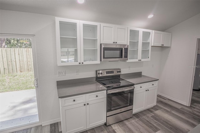 kitchen featuring vaulted ceiling, appliances with stainless steel finishes, wood-type flooring, and white cabinetry