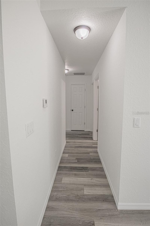 hall with wood-type flooring and a textured ceiling