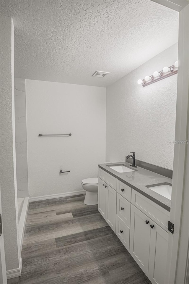 bathroom with hardwood / wood-style floors, toilet, vanity, and a textured ceiling