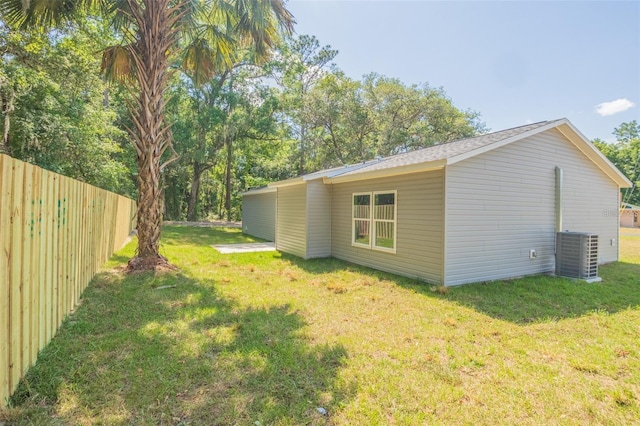 view of side of property featuring cooling unit and a yard