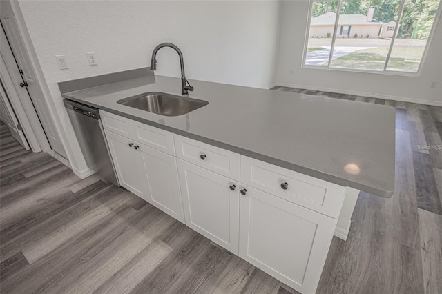 kitchen with white cabinetry, a center island with sink, dark hardwood / wood-style floors, stainless steel dishwasher, and sink