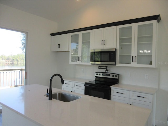 kitchen featuring electric range, glass insert cabinets, stainless steel microwave, white cabinetry, and a sink