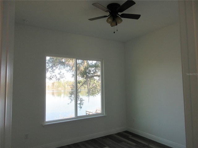 unfurnished room with dark wood finished floors, a water view, plenty of natural light, and baseboards