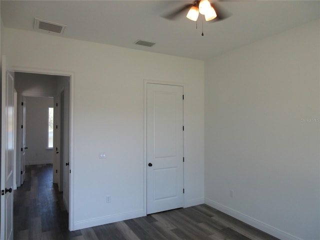 unfurnished bedroom with dark wood-style floors, visible vents, and baseboards