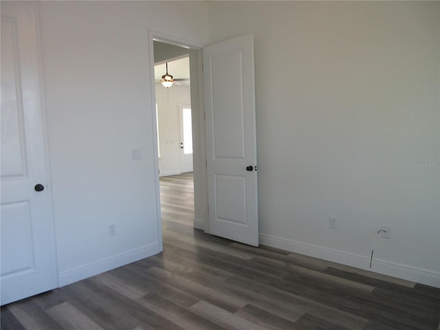 empty room featuring dark wood-style floors, baseboards, and a ceiling fan