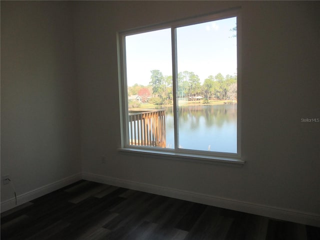 unfurnished room featuring a water view, baseboards, and dark wood finished floors