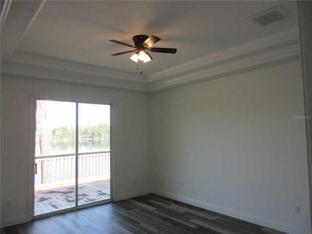 empty room featuring dark wood finished floors, visible vents, a water view, ornamental molding, and baseboards