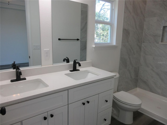 bathroom featuring toilet, a stall shower, double vanity, and a sink