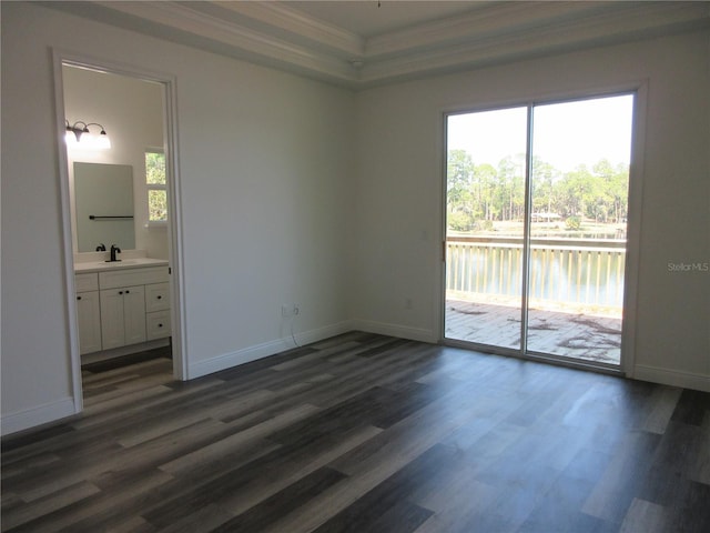 unfurnished bedroom featuring access to exterior, dark wood finished floors, crown molding, and a sink