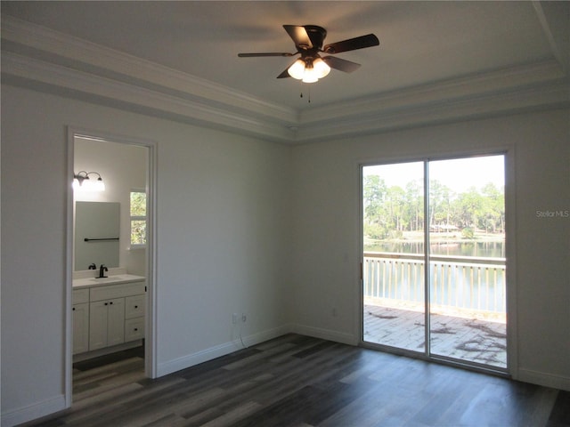 unfurnished bedroom featuring dark wood finished floors, a water view, access to outside, crown molding, and a sink