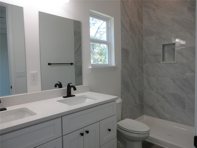 bathroom with double vanity, a sink, toilet, and a shower stall