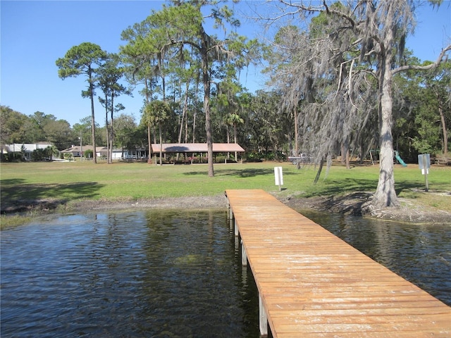 view of dock with a water view and a lawn