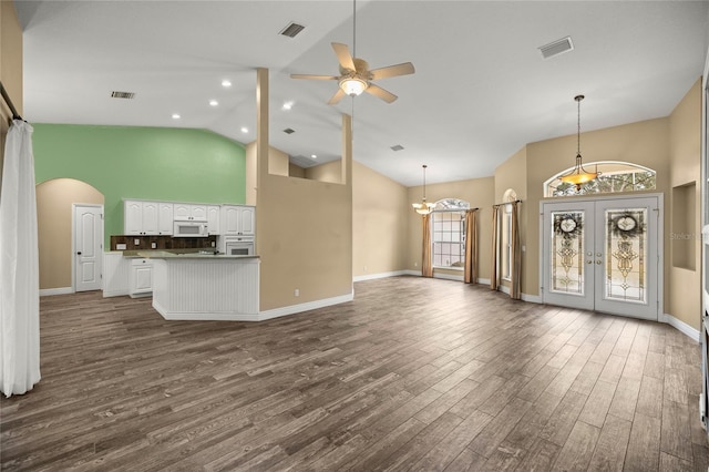 unfurnished living room featuring dark hardwood / wood-style flooring, ceiling fan with notable chandelier, french doors, and high vaulted ceiling