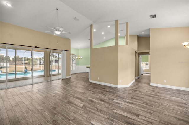 spare room featuring plenty of natural light, ceiling fan with notable chandelier, hardwood / wood-style floors, and high vaulted ceiling