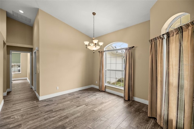 empty room featuring a chandelier and hardwood / wood-style flooring