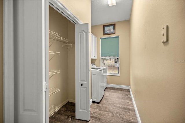 clothes washing area featuring wood-type flooring, separate washer and dryer, and cabinets