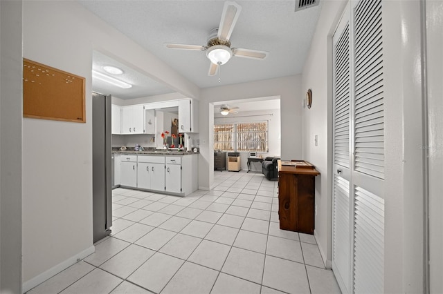 kitchen with white cabinetry, ceiling fan, a textured ceiling, and light tile patterned flooring