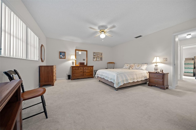 bedroom with ceiling fan, light colored carpet, and a textured ceiling