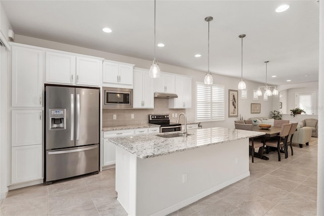 kitchen featuring decorative light fixtures, backsplash, white cabinetry, an island with sink, and stainless steel appliances