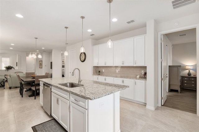 kitchen with decorative light fixtures, a kitchen island with sink, white cabinets, and sink