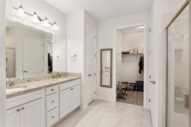 bathroom featuring a shower with shower door and vanity