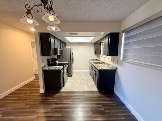 kitchen with wood-type flooring, sink, stainless steel appliances, a textured ceiling, and light stone counters