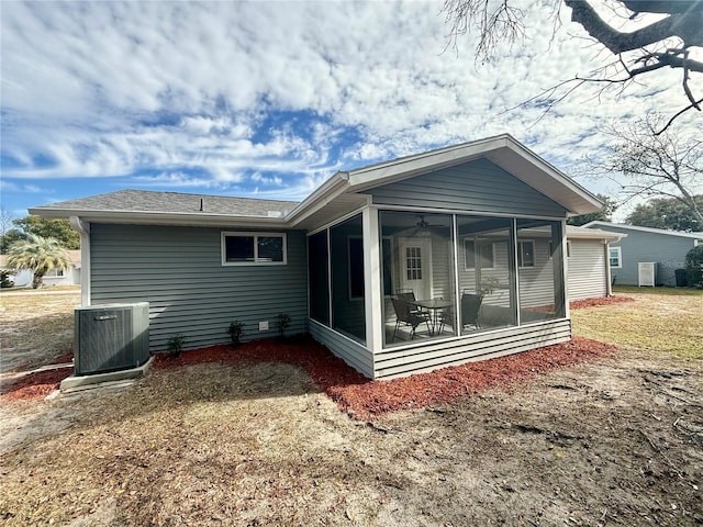 rear view of property with a sunroom, a lawn, and central AC unit