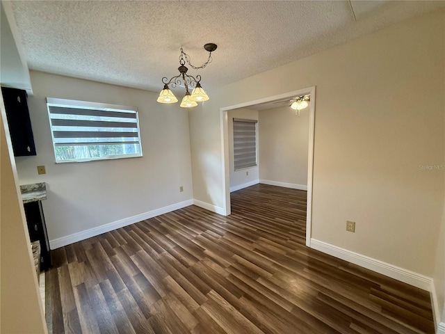 unfurnished dining area with dark wood-type flooring, a notable chandelier, and a textured ceiling