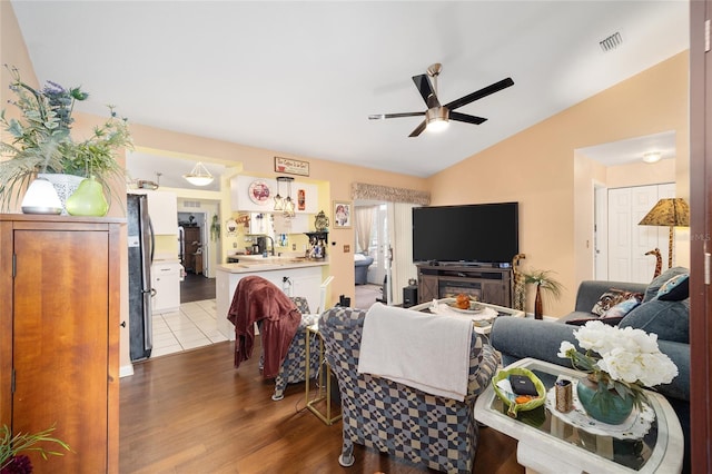 living room featuring lofted ceiling, ceiling fan, and light hardwood / wood-style flooring