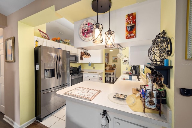 kitchen with light tile patterned floors, stainless steel appliances, hanging light fixtures, white cabinets, and sink