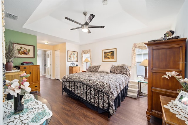 bedroom featuring ceiling fan, multiple windows, a tray ceiling, and ensuite bath