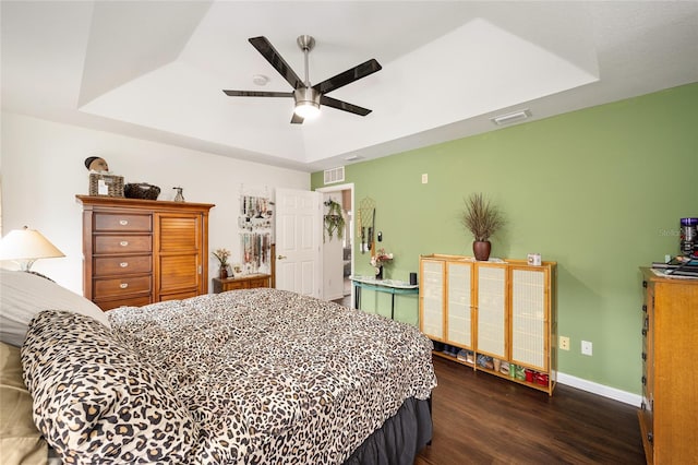 bedroom with ceiling fan, dark wood-type flooring, and a tray ceiling