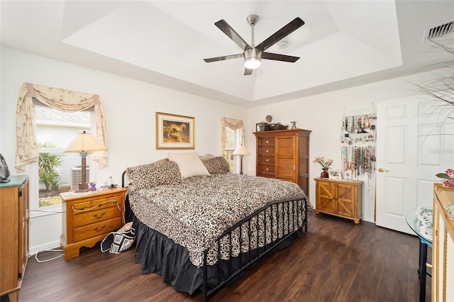 bedroom featuring ceiling fan, dark wood-type flooring, and a raised ceiling