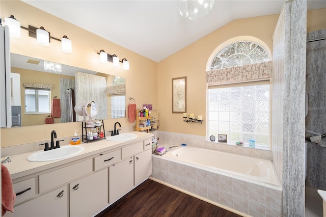 bathroom featuring vaulted ceiling, tiled bath, hardwood / wood-style floors, and vanity