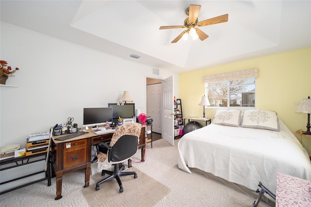 carpeted bedroom with ceiling fan, a closet, and a raised ceiling