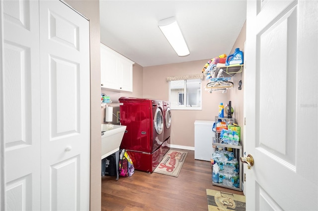 laundry room featuring dark wood-type flooring, separate washer and dryer, and cabinets