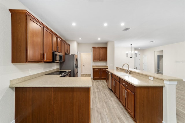 kitchen featuring light hardwood / wood-style floors, kitchen peninsula, sink, hanging light fixtures, and stainless steel appliances