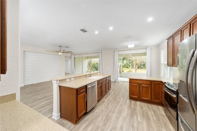 kitchen with ceiling fan, light wood-type flooring, sink, and stainless steel appliances